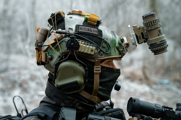 Wall Mural - Closeup head of military man in helmet, uniform and mast. Soldier in the winter forest. Vertical photo.