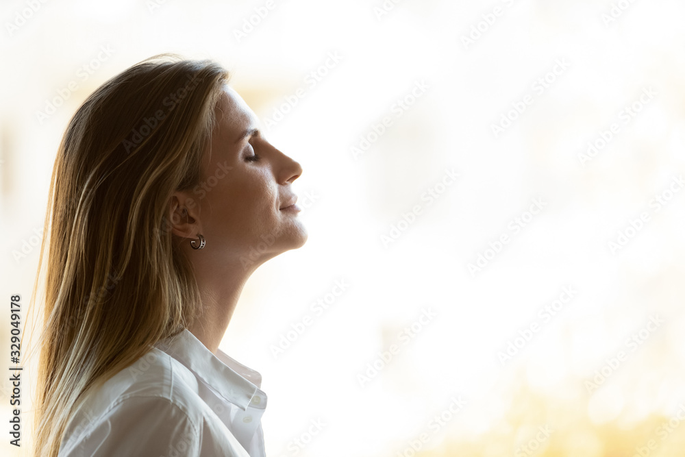 Side view close up head shot young mindful businesswoman breathing fresh air, managing stress at office. Calm peaceful millennial female manager, company owner or team leader meditating at workplace.