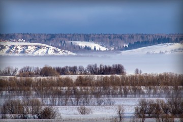  winter landscape with trees and fog over a frozen river