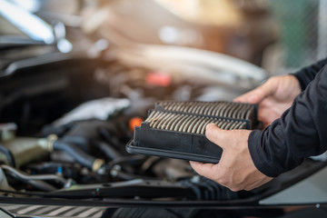 Wall Mural - Professional mechanic man holding air filter of a car for repair and preventive maintenance car in garage