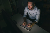 Fototapeta Tęcza - Bearded man working on computer long hours 