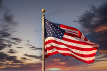 An American Flag On Flagpole Waving In The Wind Under Clear Blue Skies