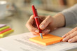 © PheelingsMedia - Woman writing to do list on sticky notes on a desk at home