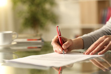 Woman Signing Document With Pen On A Desk At Home