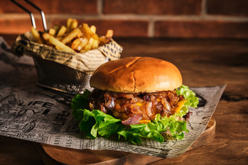 Wall Mural - Burger with beef and caramelized onions on a wooden board. Cheeseburger with onion and beef. Juicy Delicious Homemade Burger.