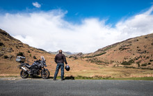 A Motorcycle Rider Takes A Break From His Journey To Appreciate The View In The English Lake District.
