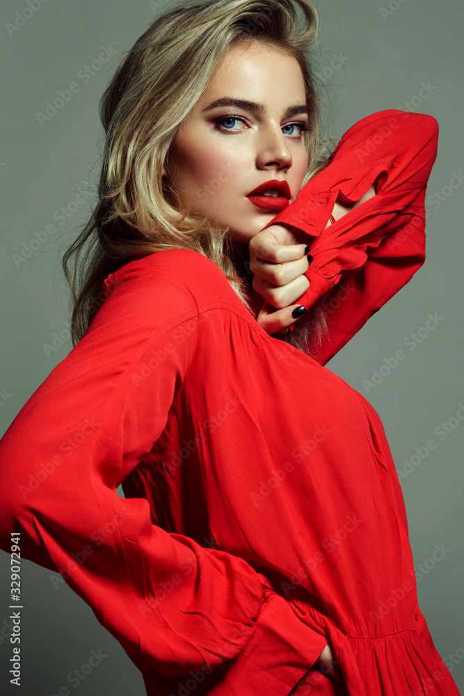 A beautiful young bright girl in a red long dress is dancing in the ...