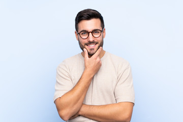 Wall Mural - Young handsome man with beard over isolated blue background laughing