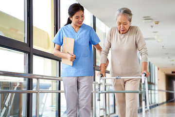 asian old woman walking with a walker in rehab center