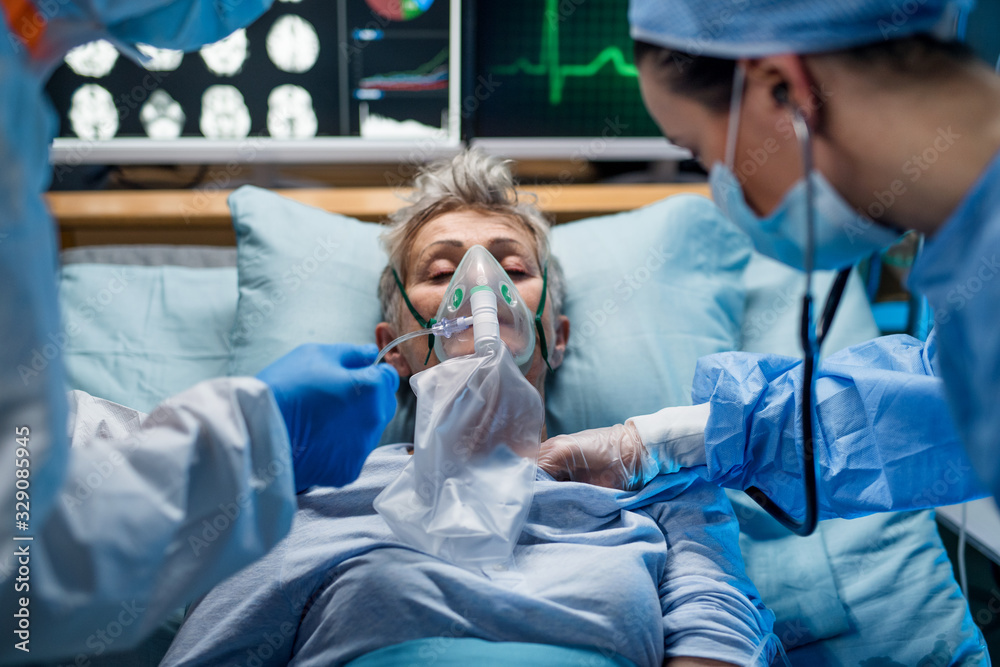 Doctors examining coronavirus infected patient lying on bed in hospital - obrazy, fototapety, plakaty 