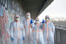 People With Protective Suits And Respirators Outdoors, Coronavirus Concept.