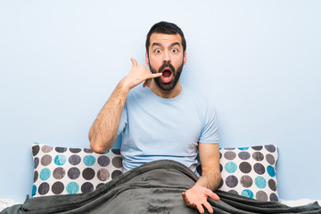 Wall Mural - Man in bed making phone gesture and doubting
