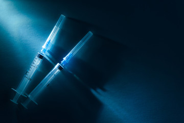 Two disposable syringes on a dark blue dramatic background. Vaccination and virus protection concept