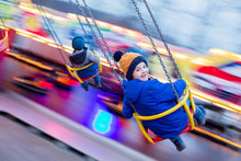 Child, cute boy riding chain swing carousel on sunset, motion blur