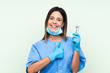 © luismolinero - Woman dentist holding tools over isolated green background giving a thumbs up gesture