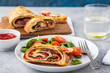 Italian food Pizza roll stromboli with cheese, salami, spinach and red pepper a light background.