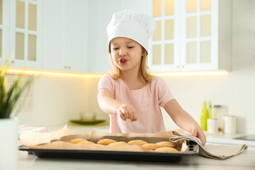 Wall Mural - Little girl wearing chef hat baking cookies in kitchen