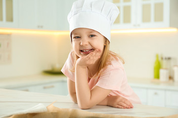 Wall Mural - Portrait of cute little girl wearing chef hat in kitchen