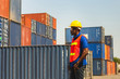 Worker man in hardhat and safety vest standing at containers cargo, Foreman control loading containers box from cargo