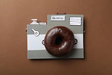 Camera Made From Donut And Piece Of Cardboard On Brown Background, Top View