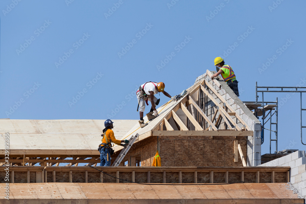 Workers are working on the roof at construction - obrazy, fototapety, plakaty 