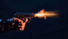 The Hand Presses The Trigger Of The Gun And The Flame From The Shot Escapes From Its Muzzle