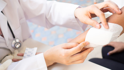 Doctor is using cotton dressing a wound at a women arm.