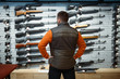 © Nomad_Soul - Man at showcase with rifles, back view, gun shop