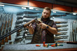 © Nomad_Soul - Man looks on rifle barrel at counter in gun shop