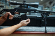 © Nomad_Soul - Male person loads sniper rifle in gun shop