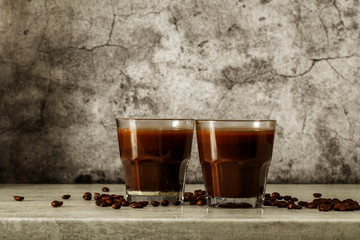 Wall Mural - Iced coffee with milk on a dark background. Coffee with ice and cream on a gray background close-up.