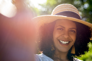 Wall Mural - Smiling woman wearing a sun hat and talking selfies