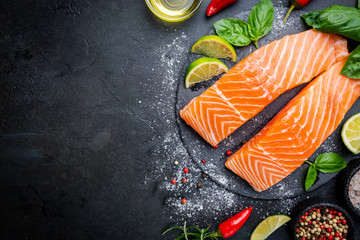 Wall Mural - Raw salmon fillet and ingredients for cooking, seasonings and herbs on a dark background . Top view