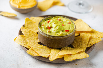 Wall Mural - Nachos chips in a bowl with sauces guacamole and beer over white stone background.