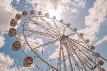 Fragment of a wheel with blue sky, clouds and sunshine in the background