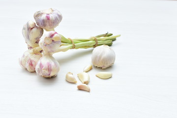 Heads of garlic, ripe white corsage on white wooden background