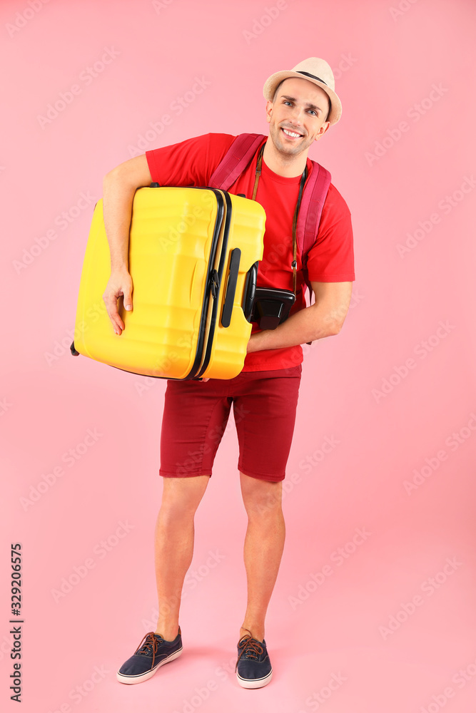 Male tourist with luggage on color background