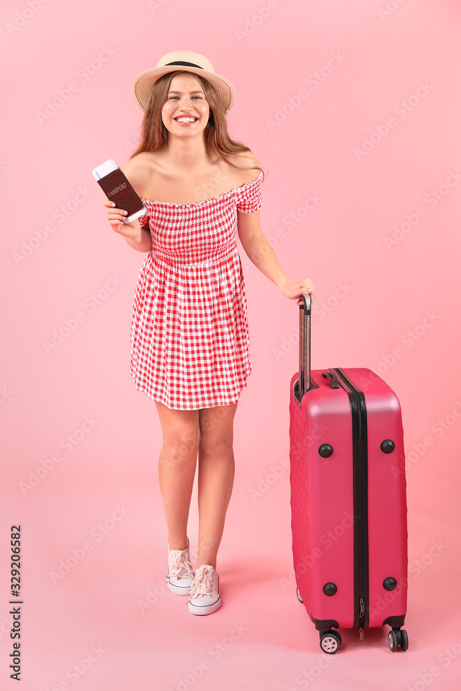 Female tourist with luggage on color background