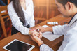 © Have a nice day  - asian male doctor wearing a scrub lab coat with a stethoscope around his neck holding a patience’s hands with two fingers on patients wrist checking pulse and heartrate, with a tablet on the table...