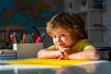 Fototapete - Educational process. Cute pupil with funny face schooling work. Cute little preschool kid boy with teacher study in a classroom.