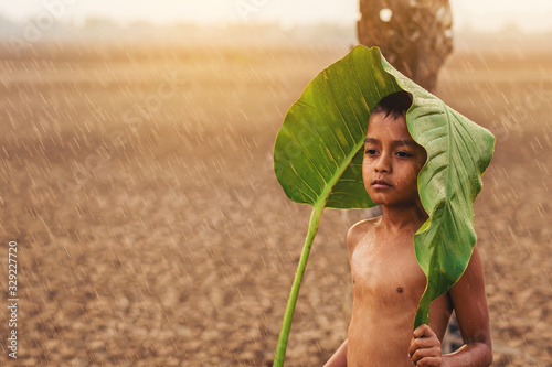 Fotomural Climate change, Asian boys waiting for something with first falling rain season on dry cracked land