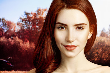 Redhead woman with perfect skin over autumn park background.