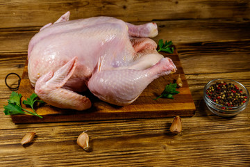 Raw whole chicken with spices on a wooden table