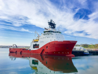 SCRABSTER, SCOTLAND - 2016 MAY 12. Offshore vessel AHTS Siem Opal moored inside harbour of Scrabster with blue skye and white clouds in the background.