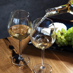 Wall Mural - Pouring white wine from bottle into the wineglass on the table