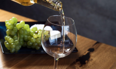 Wall Mural - Pouring white wine from bottle into the wineglass on the table