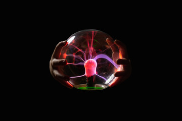 Plasma lamp wrapped by 2 hands against a black background. image. abstract shiny plasma motif