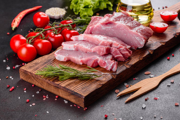 Fresh pieces pork ready to cook on a dark background in the kitchen