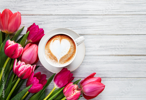 Coffee cup with latte art and pink tulips on the wood table Poster Mural XXL