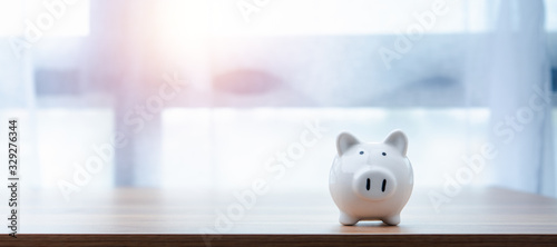 Fotografía white piggy Bank on a window light background with copyspace for design